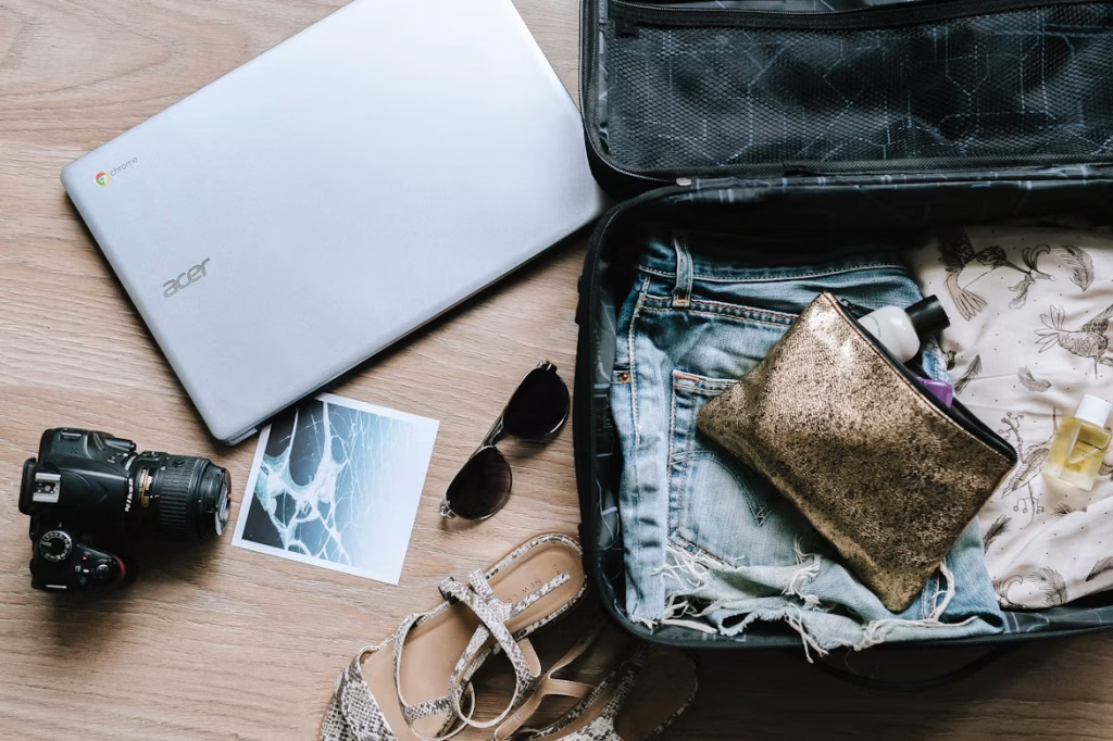 Open suitcase with travel clothes, camera, sunglasses, and accessories